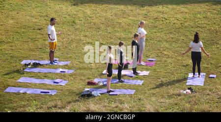 Lezione di yoga tenuto sull'erba in un giardino pubblico, Brighton & Hove, East Sussex, Engerd, Regno Unito. Foto Stock
