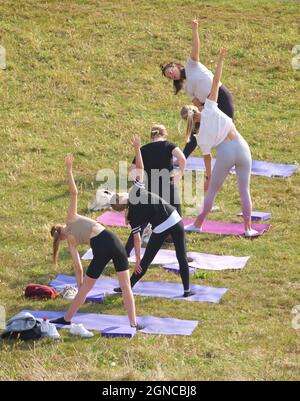 Lezione di yoga tenuto sull'erba in un giardino pubblico, Brighton & Hove, East Sussex, Engerd, Regno Unito. Foto Stock