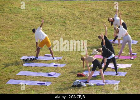 Lezione di yoga tenuto sull'erba in un giardino pubblico, Brighton & Hove, East Sussex, Engerd, Regno Unito. Foto Stock