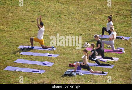 Lezione di yoga tenuto sull'erba in un giardino pubblico, Brighton & Hove, East Sussex, Engerd, Regno Unito. Foto Stock