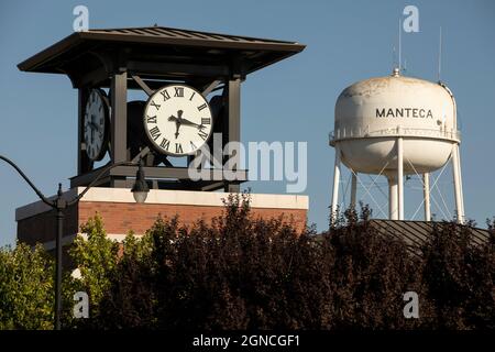 Manteca, California, USA - 15 luglio 2021: Il sole del pomeriggio splende sulla torre dell'orologio della città e sulla famosa torre dell'acqua. Foto Stock