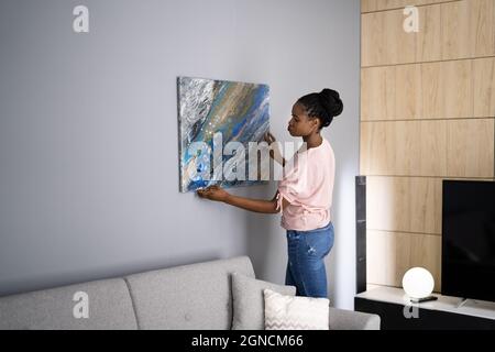 Donna sorridente che appica la pittura o l'immagine all'interno Foto Stock