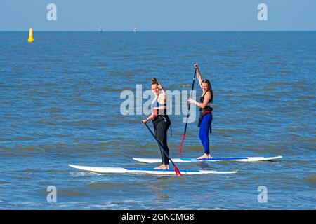 Due pedalò femmina che praticano lo sport acquatici, lo stand up paddleboard / stand up paddleboard / SUP lungo la costa del Mare del Nord Foto Stock