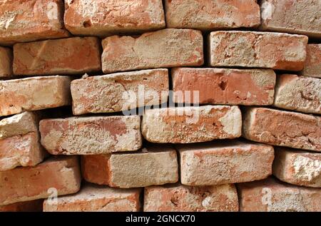 un muro di pietra irregolare fatto di vecchi mattoni rossi Foto Stock