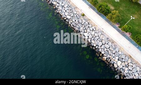 Vista con droni di un argine costiero a Istanbul sul mare di Marmara. Costa con rocce di pietra e parco. Blu acqua di mare verde Foto Stock