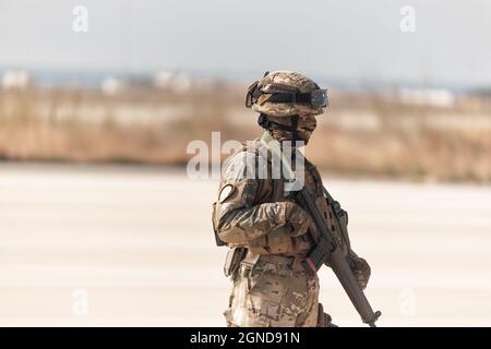 Soldato moderno in completo equipaggiamento protettivo che tiene fucile d'assalto Foto Stock