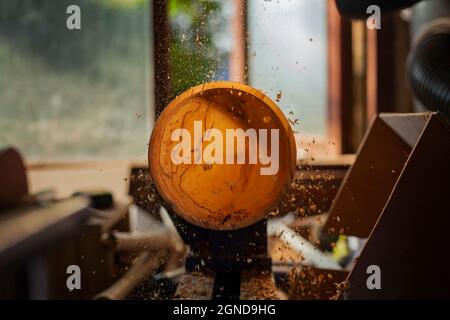 Una ciotola di legno che è girata da un uomo su un tornitori lathe.A artigiano a work.Sawdust sta volando. Foto Stock