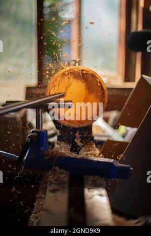 Una ciotola di legno che è girata da un uomo su un tornitori lathe.A artigiano a work.Sawdust sta volando. Foto Stock