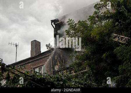 Incendio in un edificio residenziale a cinque piani. I vigili del fuoco spengono il fuoco con acqua da un cannoniere. Foto Stock