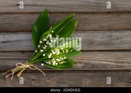 Fiori parzialmente sfocati su una superficie di legno. Un bouquet di gigli della valle sulle tavole. Vista dall'alto. Spazio di copia Foto Stock