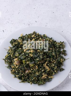 piatto di foglie di moringa o di bastone, mescolato con cocco grattugiato e temperato con olio, piatto vegetariano sano su un piatto, closeup Foto Stock