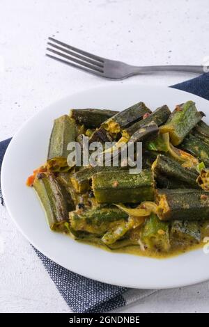 piatto di okra o okro, anche noto come le dita delle signore, servito curry vegetariano sano, su superficie bianca tavolo Foto Stock