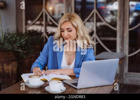 Bella donna freelance, blogger, influencer con laptop funziona a distanza e beve caffè. Un fotografo come hobby. Messa a fuoco selettiva soft. Foto Stock