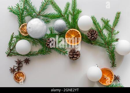 Set decorativo di Natale composto da palle bianche di Natale, rametti di abete rosso, coni, arance e limoni essiccati e anice. Vista dall'alto. Sfondo bianco. Foto Stock