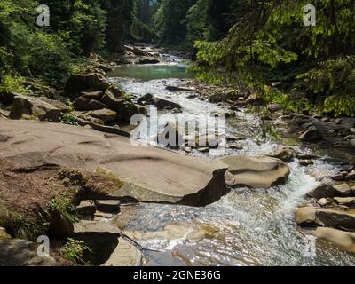 Piccolo fiume che scorre rapidamente e vividamente attraverso la sua valle rocciosa selvaggia Foto Stock