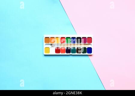 Un set di vernici e matite per disegnare su sfondo rosa. Cancelleria per la scuola. Disposizione delle merci per l'artista. Vista dall'alto. Foto Stock