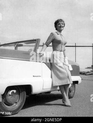 SYLVIA SYMS circa 1957 pone accanto alla pubblicità dell'automobile per la British Picture Corporation associata Foto Stock