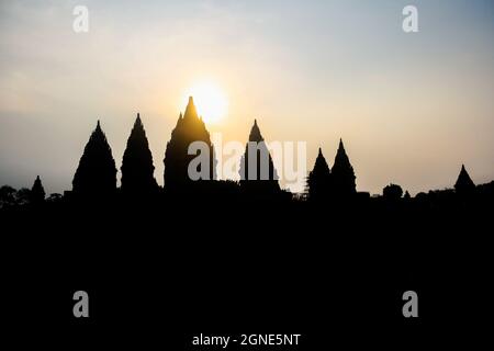 Silhouette dell'antico complesso del tempio Prambanan durante il tramonto a Yogyakarta, Indonesia, con sfondo cielo blu e arancione. Nessuna gente. Foto Stock