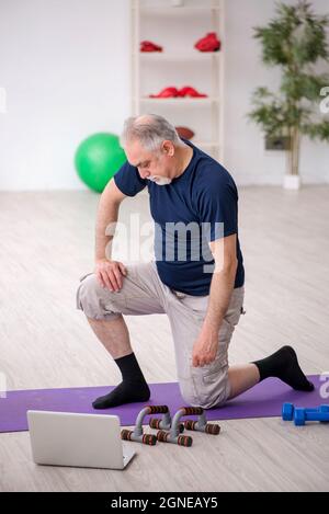 L'uomo anziano fa esercizi sportivi a casa Foto Stock