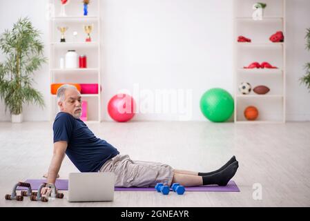 L'uomo anziano fa esercizi sportivi a casa Foto Stock