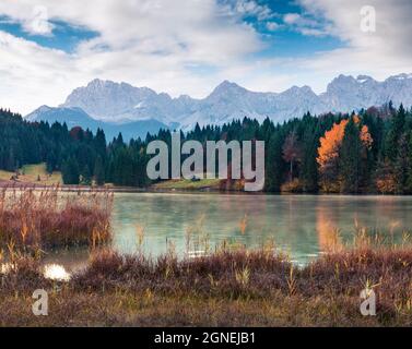 Scena Misty mattina del lago di Wagenbruchsee con la catena montuosa Kaltwasserkar Spitze sullo sfondo. Beautifel vista autunnale delle Alpi Bavaresi, Germania, EUR Foto Stock