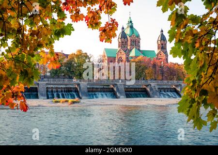 Splendida vista autunnale della chiesa protestante di San Luca Landmark e del fiume Isar. Luminoso paesaggio urbano mattutino di Monaco, Baviera, Germania, Europa. In viaggio Foto Stock