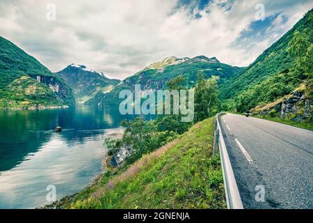 Cavalcando una moto sulla strada sulla riva del fiordo Sunnylvsfjorden. Colorata vista mattutina della Norvegia occidentale, Europa. Concetto di viaggio background. Foto Stock