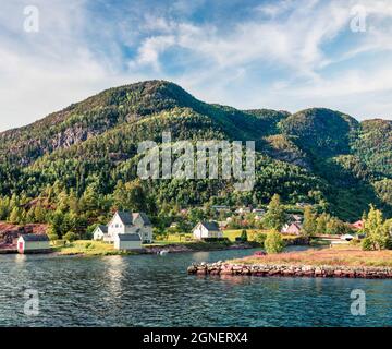 Soleggiata vista estiva del tipico villaggio norvegese sulla riva del fiordo. Scena mattutina luminosa della Norvegia, Europa. Concetto di viaggio background. Foto Stock