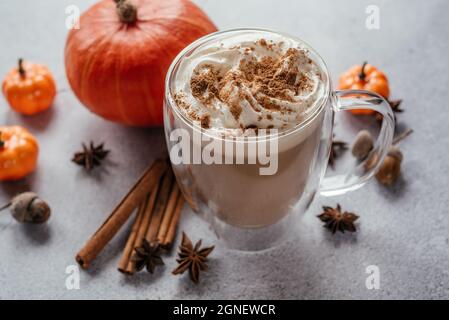 Latte speziato di zucca d'autunno con panna montata e cannella, bevande calde vegane d'autunno con spezie, cannella e stelle di anice Foto Stock
