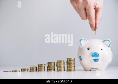 mano umana che inserisce la moneta piggybank. Alta qualità e risoluzione bellissimo concetto di foto Foto Stock