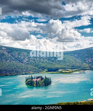 Incredibile vista mattutina dell'isola di Visovac e del monastero francescano del XVII secolo. Scena estiva aerea del Parco Nazionale di Krka, Croazia, Europa. Abbellito Foto Stock