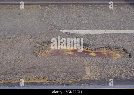 Pothole molto grande e profondo in tarmac al ponte Foto Stock