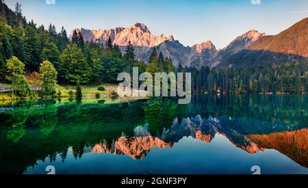 Tranquilla vista mattutina del lago Fusine. Colorata alba estiva nelle Alpi Giulie con la vetta del Mangart sullo sfondo, provincia di Udine, Italia, Europa. Bellezza di Foto Stock