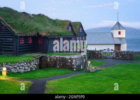 Vecchia casa colonica in tronchi di Kirkjuboargardur con tetto di erba sintetica nel villaggio di Kirkjubour su Streymoy, Isole Faroe Foto Stock