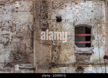 Muro di mattoni rossi rotto e intonaco danneggiato sullo sfondo Foto Stock