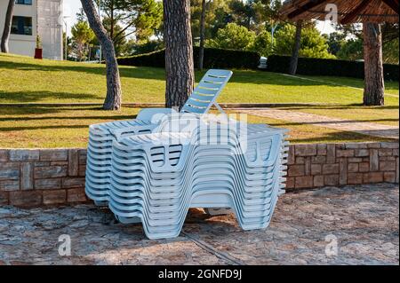 sulla spiaggia troverete una pila di lettini. Sul terrapieno ci sono sdraio pulite la sera Foto Stock