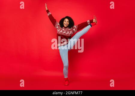 Intera lunghezza corpo dimensione donna sorridente facendo stretching in abiti casual isolato colore rosso brillante sfondo Foto Stock