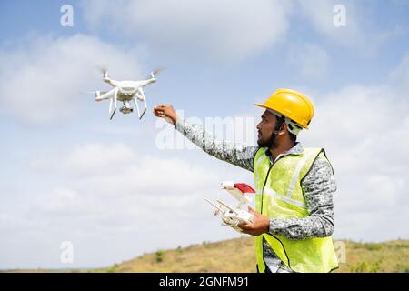 Drone Pilot riceve il drone in modo sicuro utilizzando il telecomando - concetto di ritorno a casa, indagine aerea utilizzando la tecnologia UAV Foto Stock