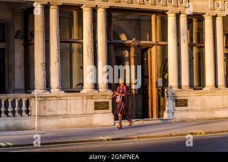 Donna che passa accanto a un edificio Horse Guards Avenue, un edificio governativo a Whitehall, Londra, Inghilterra, Regno Unito Foto Stock