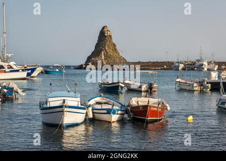 Il porto di Aci Trezza, Sicilia, con lo stack marino basalto del Faraglione Grande, uno dei Faraglioni o delle Isole dei Ciclopi Foto Stock