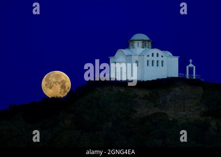 Luna piena alba accanto alla chiesa di Agios Nikolaos nel porto di Myrina Lemnos Foto Stock