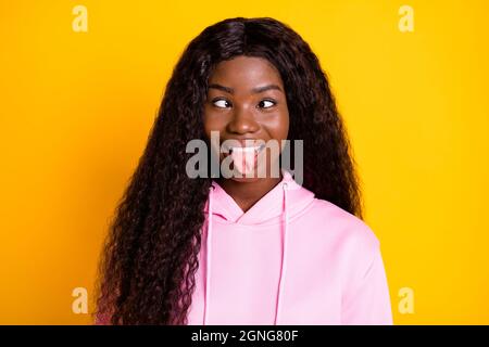 Ritratto fotografico di donna buffa afroamericana che mostra lingua isolata su sfondo giallo brillante Foto Stock