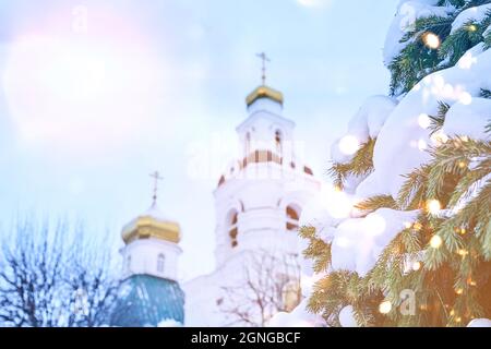 La parte superiore dorata della chiesa cristiana ortodossa, sullo sfondo del cielo blu e dei rami innevati di abete. Sfondo di Natale. Spazio per la copia. Foto di alta qualità Foto Stock