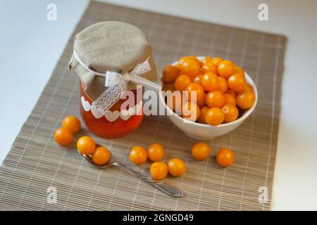 Prugne di ciliegia marmellata gialla, vitamine fresche-frutti di bosco. Marmellata fatta in casa in vaso di vetro sul marrone Foto Stock