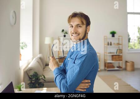 Ritratto di un bel giovane uomo d'affari in piedi con sicurezza in ufficio davanti alla fotocamera. Foto Stock