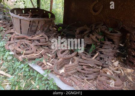 Ferro di cavallo. Cortile organizzato. Vecchie parti di macchine arrugginite usurate e utensili utilizzati nell'industria, nel trasporto, nell'agricoltura. Raggruppato per tipo e materiale Foto Stock