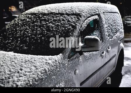 auto sotto la neve alla luce di luci per la strada, primo piano Foto Stock