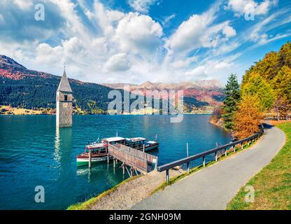 Spettacolare vista autunnale della Torre della chiesa sunken nel lago di Resia. Scena mattutina di sole delle Alpi italiane, Alto Adige, Italia, Europa. Concetto di viaggio ba Foto Stock