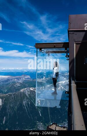 Chamonix, Francia - 10 luglio 2021. Tourist si trova nella scatola di vetro 'Step into the Void' sulla cima della montagna Aiguille Du Midi (3842m) sopra Chamonix Foto Stock