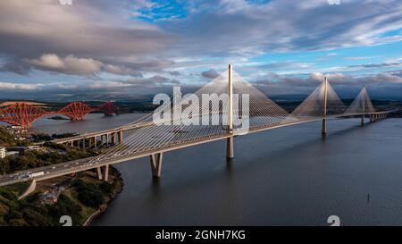 North Queensferry, Eaglesham, Scozia, Regno Unito. 25 Settembre 2021. NELLA FOTO: Vista aerea con droni dei ponti Forth. Lungo tre secoli di progettazione di ponti e collegando due delle contee scozzesi di Fife e Lothian, il ponte più recente del Queensferry Crossing Scotland progettato per assomigliarsi a vele su una nave, collega North Queensferry a South Queensferry, Con Forth Road Bridge dietro che mostra la tecnologia della metà del XX secolo e sfondo Forth Rail Bridge fine 1800 con la sua costruzione a sbalzo. Credit: Colin Fisher/Alamy Live News Foto Stock